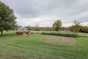 Une zone herbeuse avec une structure en bois, peut-être un abri de jardin, et un parterre circulaire.