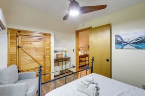 A bedroom with a bed, a wooden wardrobe, a desk with a chair, and a painting on the wall. - Cabin w/ Hot Tub, Near Mercier Orchard & Downtown (Blue Ridge)