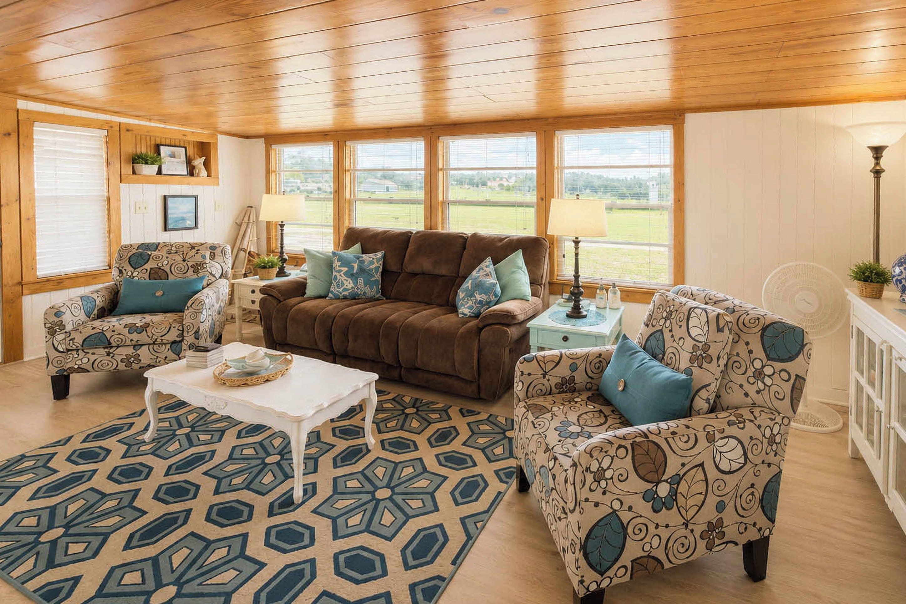 A cozy living room with a brown sofa, patterned armchairs, a white coffee table, and a geometric rug.