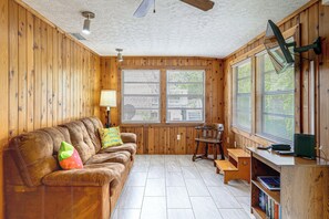 A cozy room with a wooden interior, a brown leather sofa, a wooden desk, and a bookshelf. - Parrot Head Paradise: Lake Access & Pickleball (Clermont)