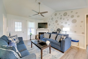 A living room with a blue sofa set, a coffee table, a fireplace, and decorative wall stickers. - Pet-Friendly Home w/ Fenced Yard Near Cherry Point (Havelock)