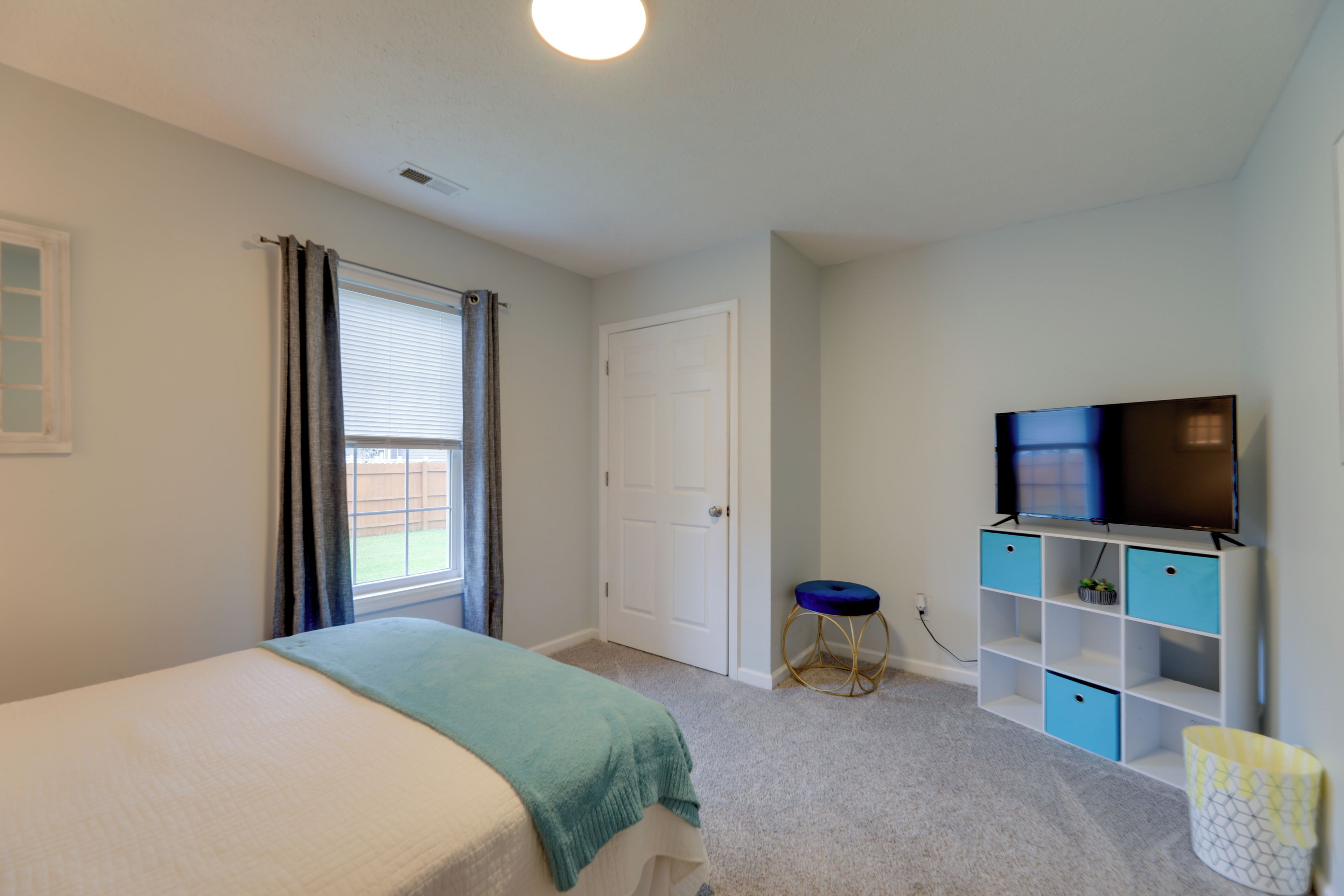 A bedroom with a bed, a television, and a desk with storage.