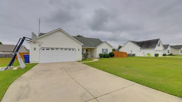 A residential street with houses, a driveway, and a basketball hoop.