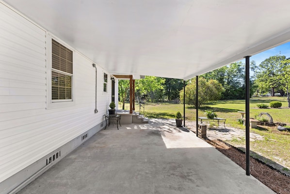 A covered porch with a concrete floor, a small table and chairs, and a potted plant. - Cute, Cozy & Near Downtown! Updated Home w/ Porch (Live Oak)