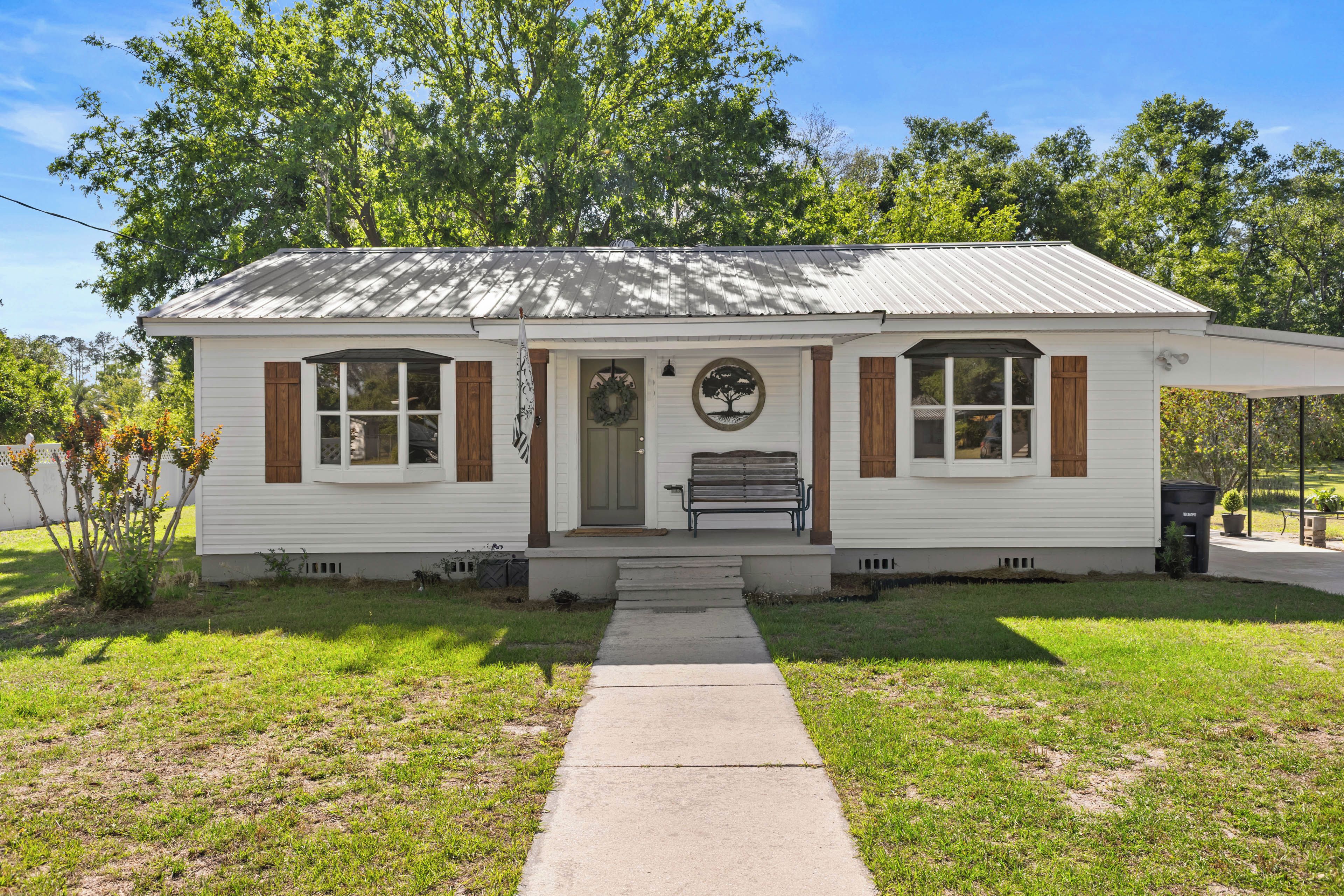 A single-story house with a front porch, a bench, and a flagpole.