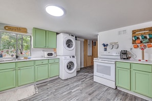 A kitchen with green cabinets, a washing machine, a microwave, and a coffee station. - Lakefront Angler's Retreat w/ Dock Access (New Haven)