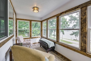 A sunroom with large windows, a bench, and a sofa. - Lakefront Angler's Retreat w/ Dock Access (New Haven)