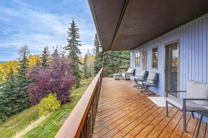 A wooden deck with outdoor seating, overlooking a forested area with autumn foliage. - Spectacular Views & Moose Sightings! Fairbanks Gem (Fairbanks)