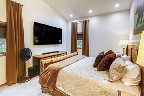 A bedroom with a bed, a flat-screen TV mounted on the wall, a wooden bedside table, a floor lamp, and a window with curtains. - Spectacular Views & Moose Sightings! Fairbanks Gem (Fairbanks)