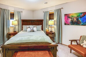 A bedroom with a wooden bed, two bedside tables with lamps, a bench, a chair, and a colorful painting on the wall. - Spectacular Views & Moose Sightings! Fairbanks Gem (Fairbanks)