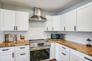 A modern kitchen with white cabinets, a stainless steel range hood, a microwave, and a built-in oven. - Dock Access, Deck & BBQ on Liberty Lake (Liberty Lake)