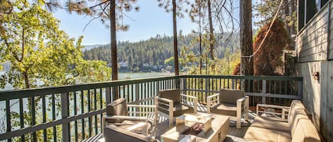 A deck with outdoor furniture overlooking a lake and forest.