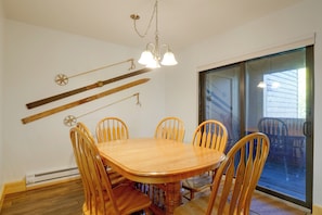 A dining area with a wooden table and chairs, a chandelier, and a sliding glass door leading to an outdoor patio. - Perfect Central Location - Walk to Base 9 Lifts (Breckenridge)