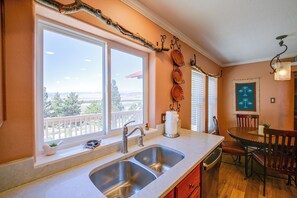 Eine Küche mit einem großen Fenster, einem Spülbecken und einem Essbereich mit Tisch und Stühlen.