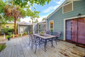 Eine Terrasse mit Tisch und Stühlen, umgeben von Grünpflanzen und einem Haus mit Garage.
