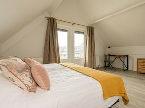A bedroom with a bed, a desk, and a view of buildings outside. - Holiday Home With 2 Bedrooms (Burgh-Haamstede)