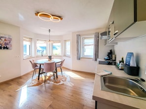 Una cocina moderna con comedor, ventanas amplias y una lámpara colgante.