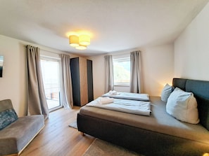 Una camera d'albergo con un letto, una sedia, una finestra e un punto luce a parete.