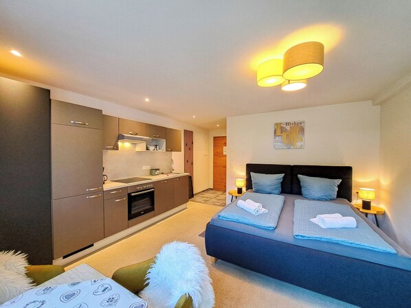 A modern bedroom with a bed, bedside tables, and a view of the kitchen. - Marchegg by Interhome (Auffach)