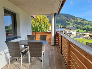 A balcony with a table and chairs, a view of a forested mountain, and a clear sky. - Marchegg by Interhome (Auffach)