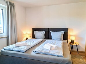 A hotel room with a double bed, two bedside lamps, a window with curtains, and a view of the outside. - Marchegg by Interhome (Auffach)