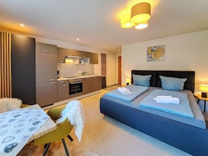 A modern hotel room with a bed, a small kitchen, a dining area, and a bathroom. - Marchegg by Interhome (Auffach)