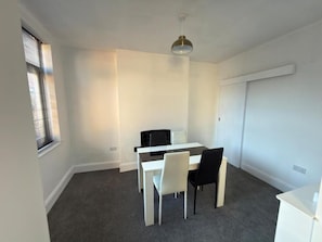 A room with a white table and chairs, a ceiling light, and a window with blinds. - Central Peterborough Home, Garden, Parking, 2 Bed (Peterborough)