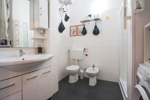 A bathroom with a sink, toilet, bidet, and a washing machine. - Borgo Dei Greci Loft (Firenze)