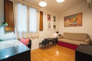 A furnished room with a sofa, a desk, a chair, a map, and a globe. - Borgo Dei Greci Loft (Firenze)
