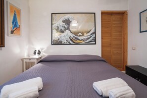 A bedroom with a bed, a nightstand, a wooden wardrobe, and a wall with a framed artwork. - Borgo Dei Greci Loft (Firenze)