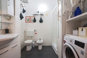 A compact bathroom with a toilet, bidet, and washing machine. - Borgo Dei Greci Loft (Firenze)