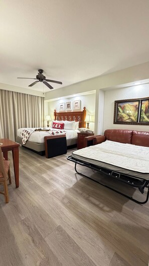 A hotel room with a bed, a sofa, a desk, and a ceiling fan. - Cozy 2-Bedroom Apartment with Shared Pool in Orlando (Orlando)