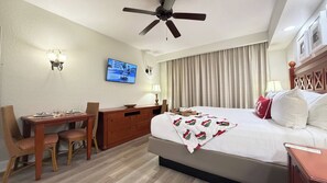 A hotel room with a bed, a desk, a chair, a television, a ceiling fan, and curtains. - Cozy 2-Bedroom Apartment with Shared Pool in Orlando (Orlando)