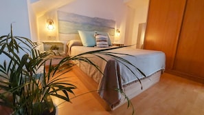 Ein Schlafzimmer mit einem Bett, Nachttischlampen, einem großen Fenster und einem Blumentopf.