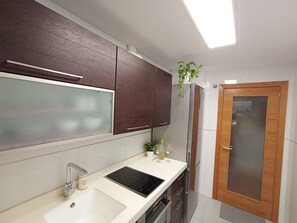 Une cuisine moderne avec un plan de travail blanc, des appareils en acier inoxydable et des meubles de cuisine en bois foncé.