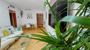 Un salon moderne comprenant un canapé, une table à manger, des chaises et une grande plante.