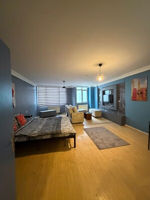 A bedroom with a bed, a sofa, a TV mounted on the wall, and a window with blinds. - Cozy 1-Bedroom Apartment in Pendik, Türkiye (Pendik)