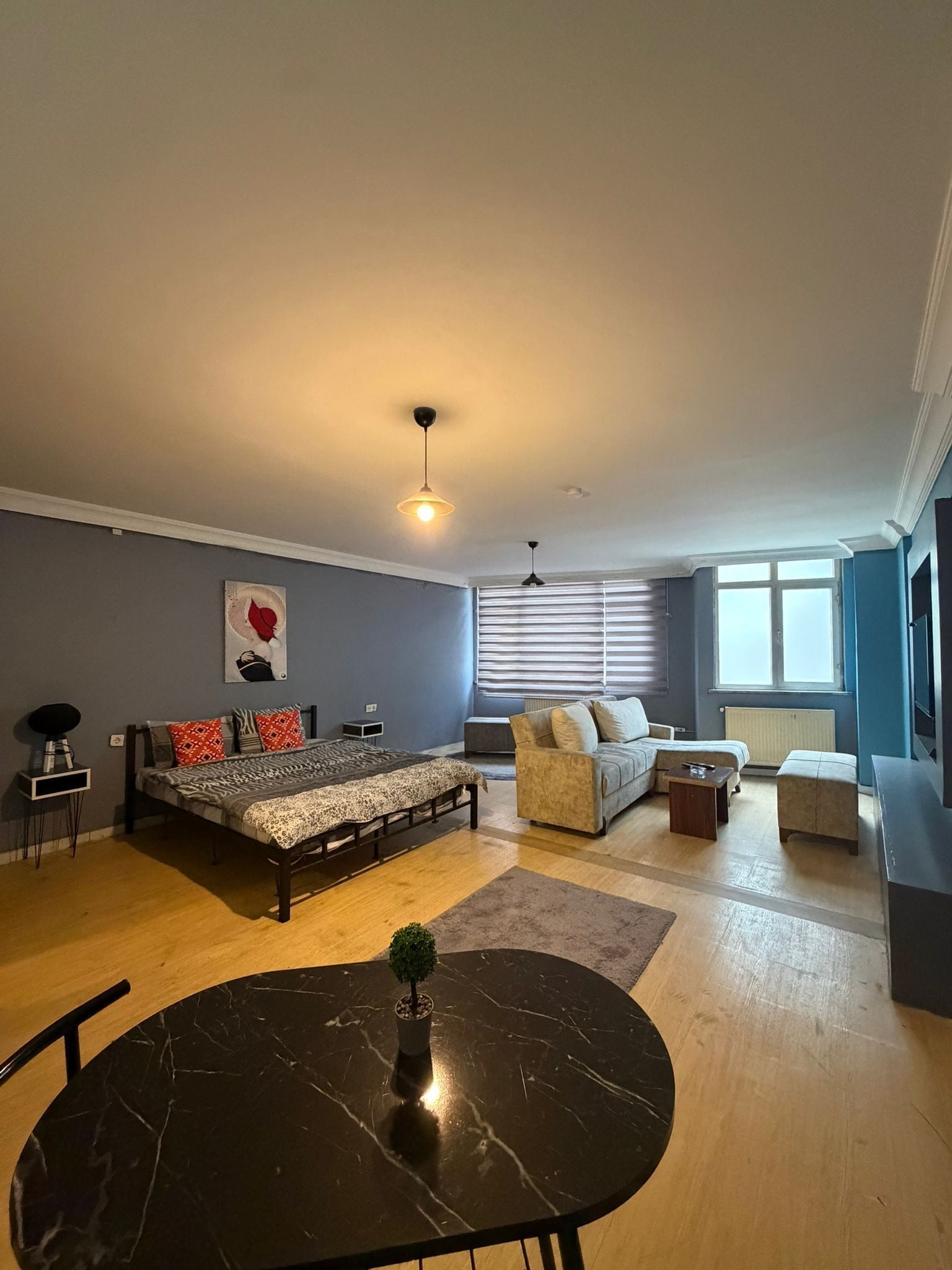A modern living room with a bed, sofa, and a dining table.