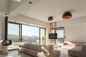 A modern living room with a sofa, a TV, and a large window offering a city view. - Dias Grand Villa - Indoor Outdoor Pools (Mylopotamos)