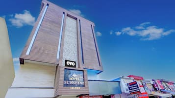 Un hotel llamado 'OYO' con un letrero que indica 'HOTEL SUNSHINE DELUXF' y una tienda de reparación móvil '2ND MOBILE REPAIRING'.