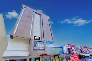 Un hotel llamado 'OYO' con un letrero que indica 'HOTEL SUNSHINE DELUXF' y una tienda de reparación móvil '2ND MOBILE REPAIRING'.