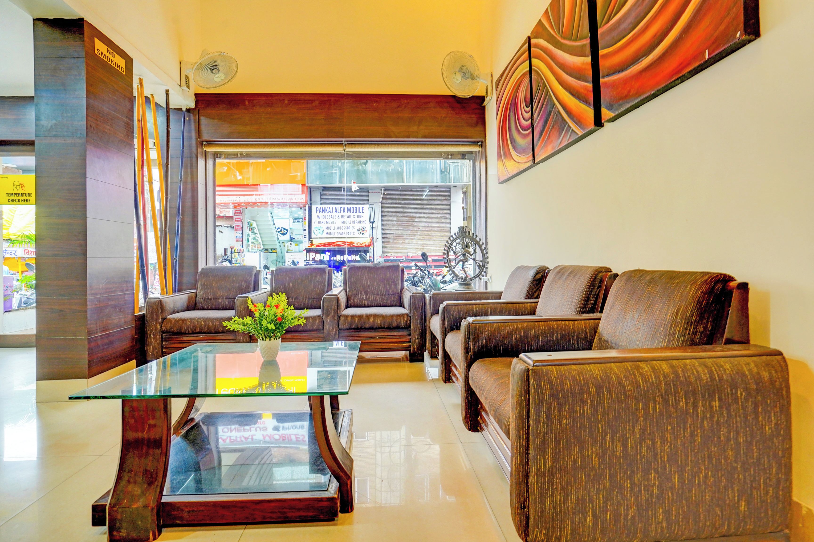 A modern lobby with leather sofas, a glass coffee table, and a view of a shop through the window.