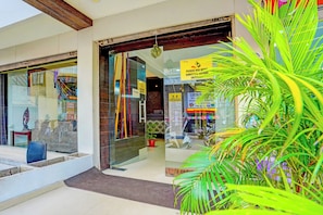 A hotel entrance with a glass door, a red mat at the entrance, and a sign requesting hand sanitizer use. - Super Hotel O Sunshin Deluxe (Nagpur)