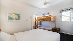Ein Zimmer mit einem Etagenbett, einem Einzelbett, einer Karte an der Wand und einem Fenster mit Vorhängen.