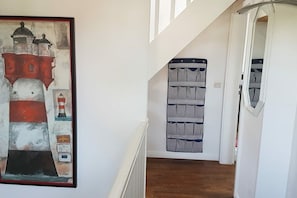 A staircase with a painting of a lighthouse, a striped wall hanging, and a mirror in a hallway. - Holiday apartment in Sylt with 1 bedroom (Hörnum\/Sylt)