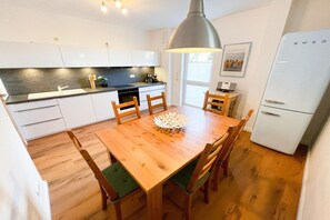 Eine kompakte Küche mit weißen Schränken, einem Holzespeisetisch und einem weißen Kühlschrank.