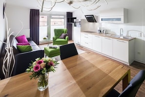 A modern living space with a dining table, a sofa, a green armchair, and a kitchen area with a sink and cabinets. - Apartment in Juist with swimming pool (Juist)