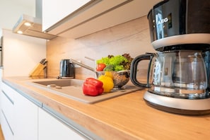 A kitchen counter with a coffee maker, a colander with vegetables, and a knife block. - Holiday apartment with 1 bedroom (Lohme OT Ranzow)