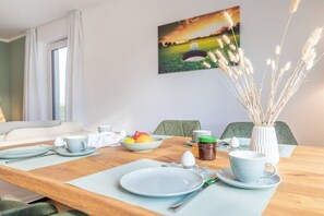 A dining table set for breakfast with plates, cups, and a bowl of fruit. - Holiday apartment with 1 bedroom (Lohme OT Ranzow)