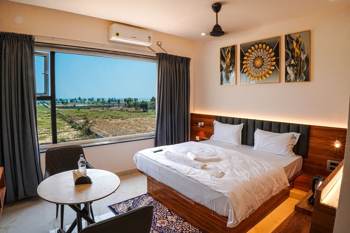 A hotel room with a large bed, a table, and a view of the outdoors.